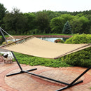 Tan hammock on a hammock stand sitting on a brick patio.