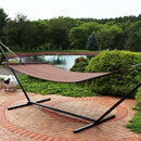 Brown rope hammock on a hammock stand sitting on a brick patio. 