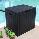 Black faux wood, square, storage deck box sitting next to a pool. 